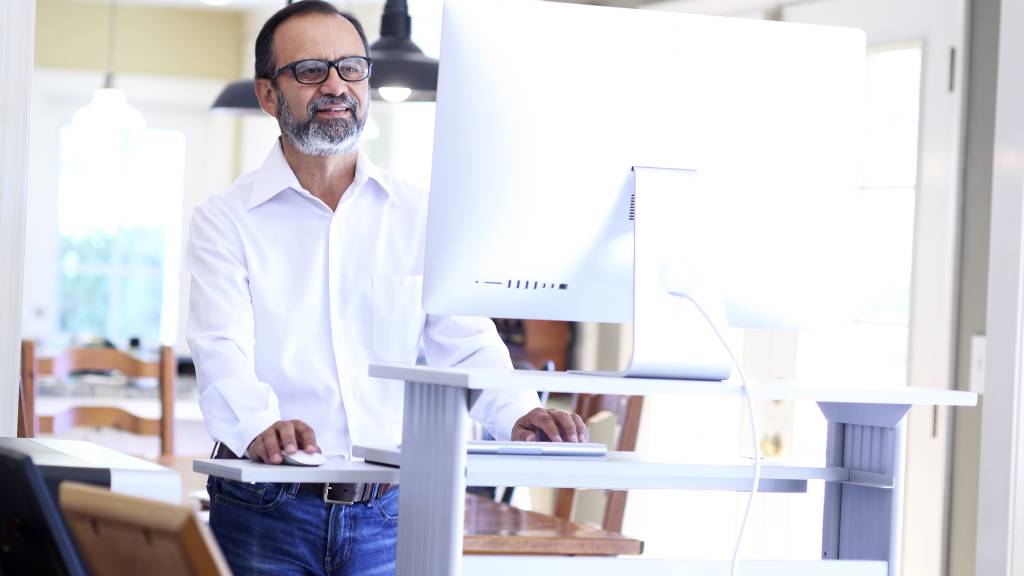 Man standing at his desk in an ergonomic home office