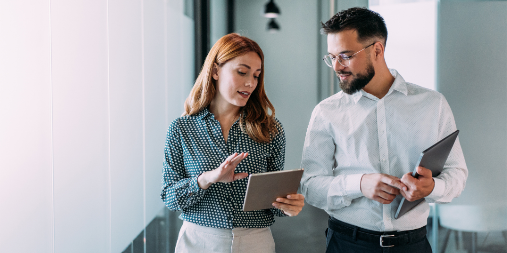 Businessman and businesswoman in meeting using digital tablet and discussing business strategy