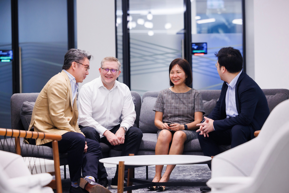 A group of professionals of different cultural backgrounds sit happily conversing.