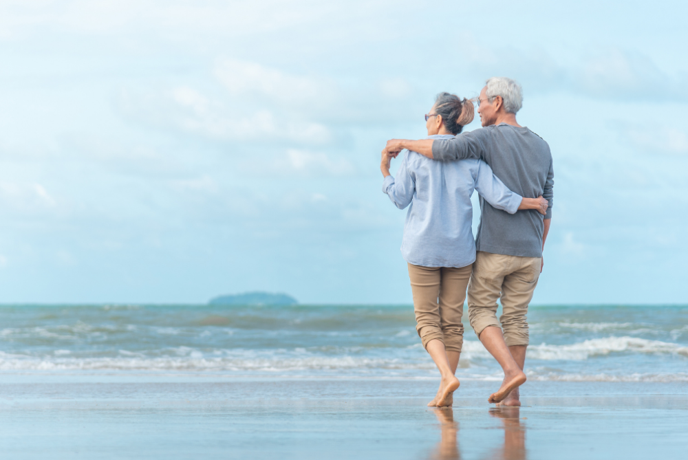 two people with grey hair stand on the shore