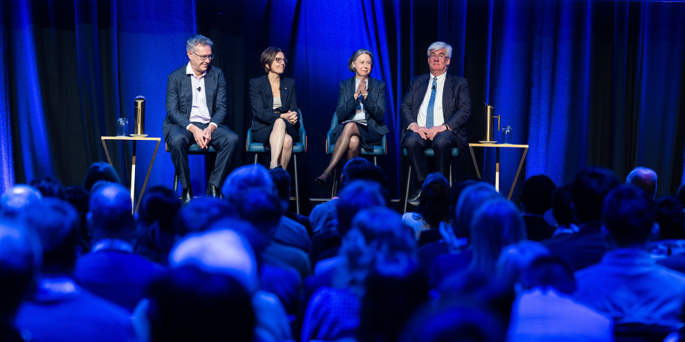 2 men and two women sit on a stage in front of an audience