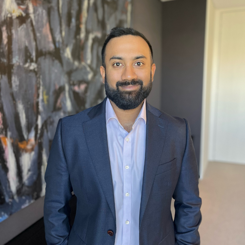 Business man with blue jacket and shirt, standing in office foyer with abstract painting in background
