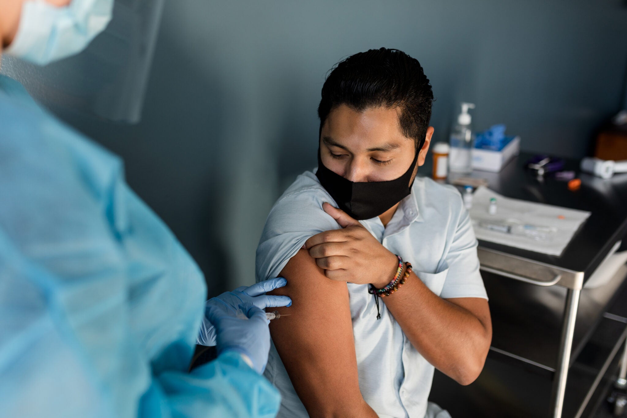 A young man rolls up his sleeve as a nurse prepares to give him the Covid-19 vaccine.