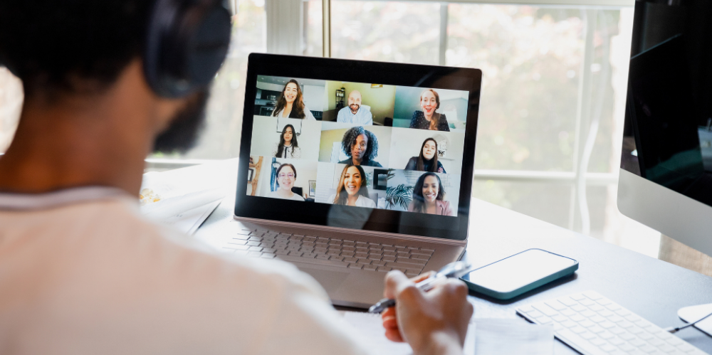 Over-the-shoulder view unrecognisable male worker attending online meeting.