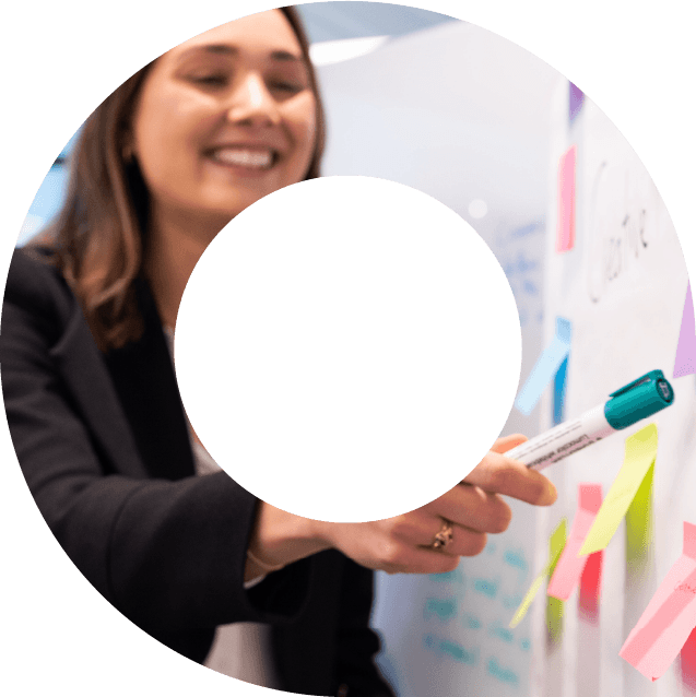 Female actuary writing on post-it-notes and pointing at whiteboard