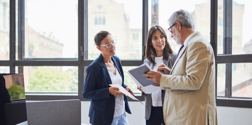 People standing together talking in an office environment. 