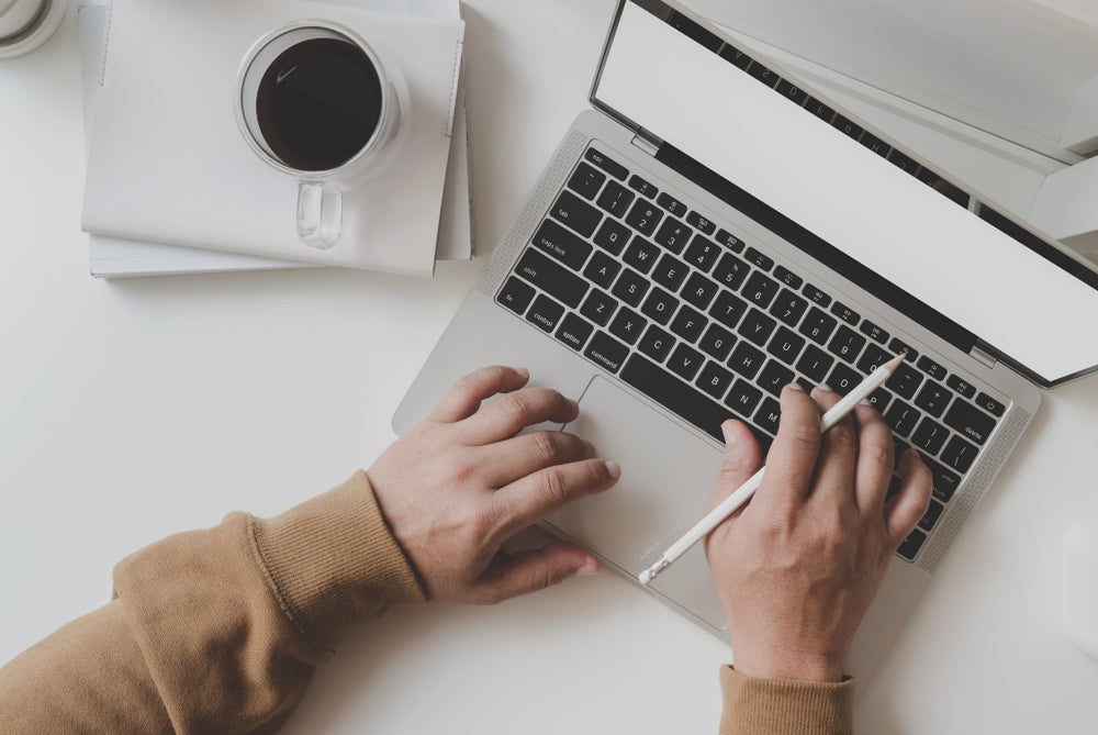 Two hands typing on a laptop