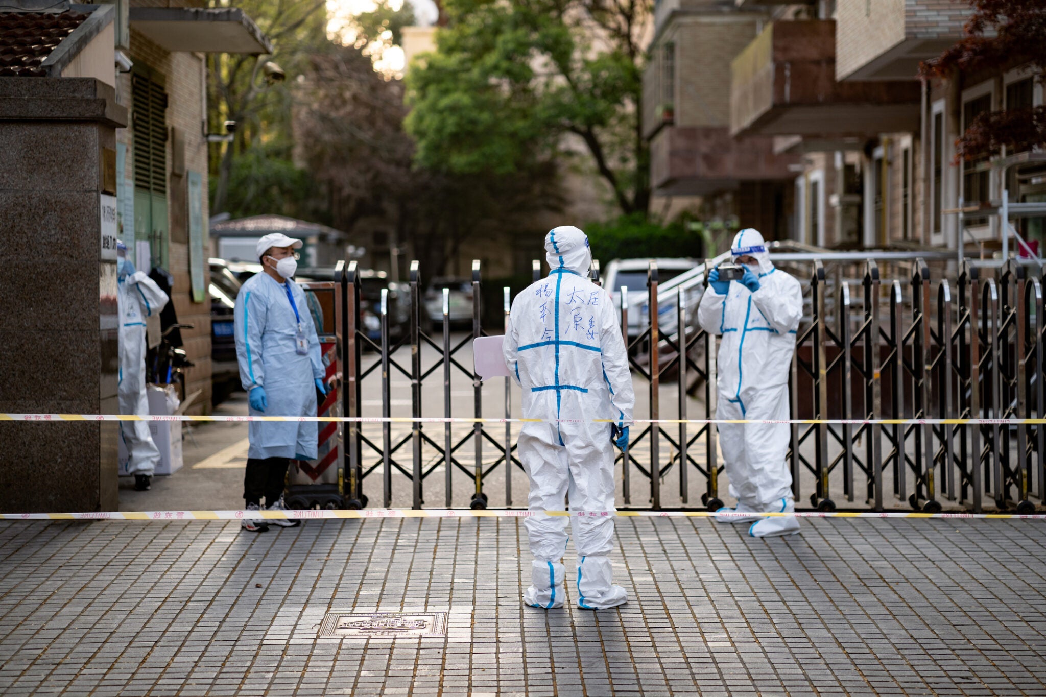 Volunteers take photos of each-other in front of a locked compound during a 4 day city wide lockdown drags on past the planned finish date as Shanghai struggles to control a large outbreak of COVID-19.