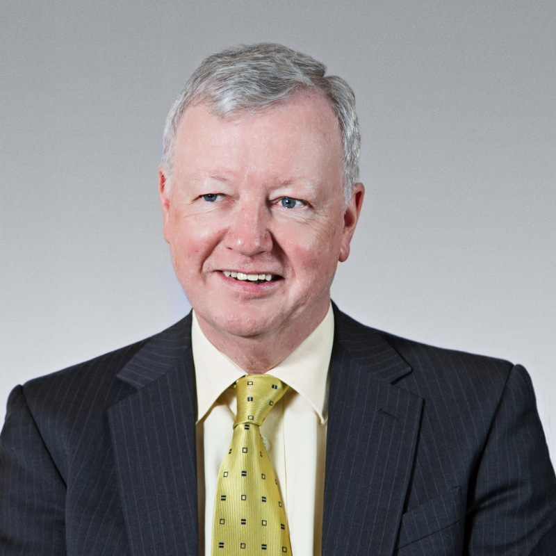 Portrait photo of Michael Rice with black suit, lemon shirt and yellow tie with black specks