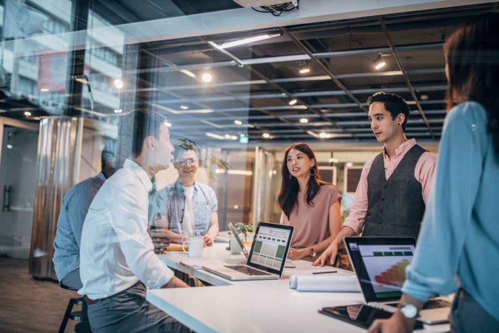 Group of people working around a desk.