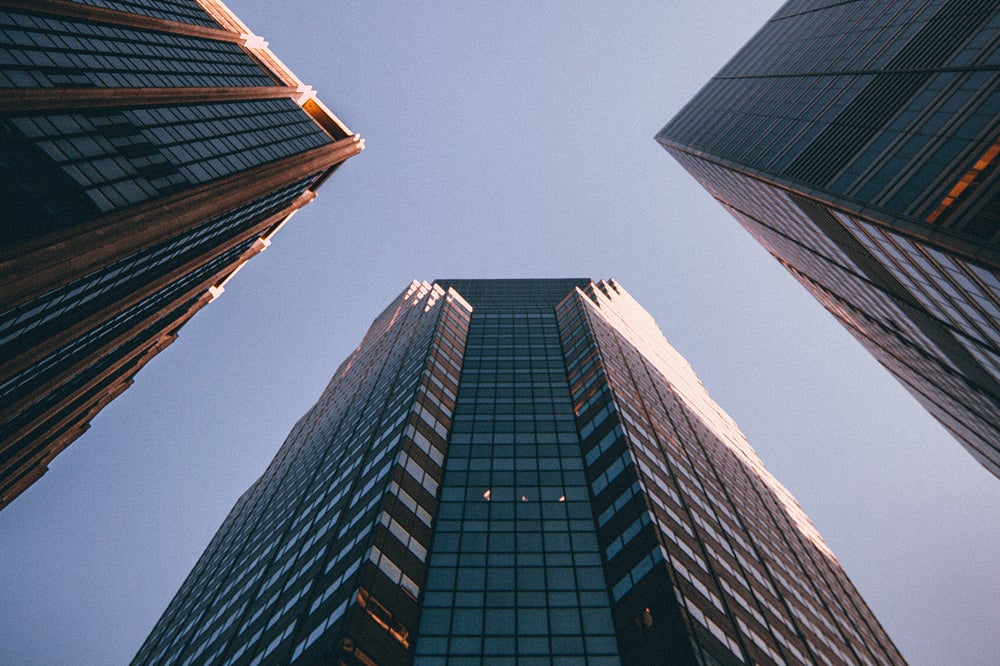 Photo looking up at tall buildings against blue sky
