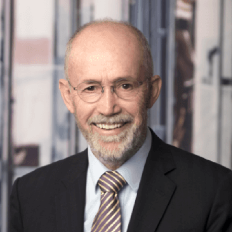 Portrait photo of Ian Laughlin with dark suit, white shirt and brown stripped tie