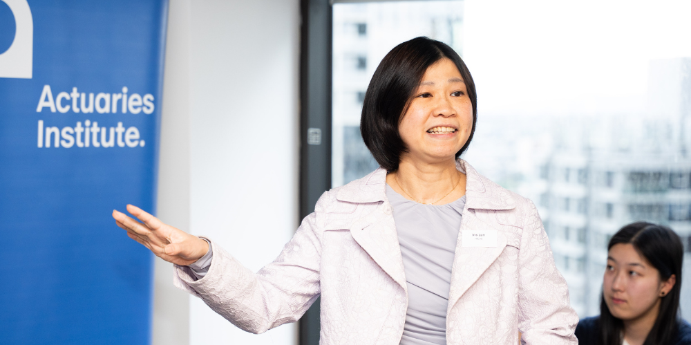 Female presenting, white jaks and light grey shirt, black hair