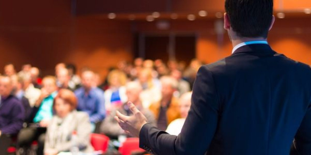 Speaker presenting in front of blurred crowd