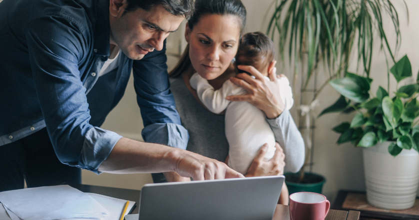 Young family with cute little baby boy going over finances at home.