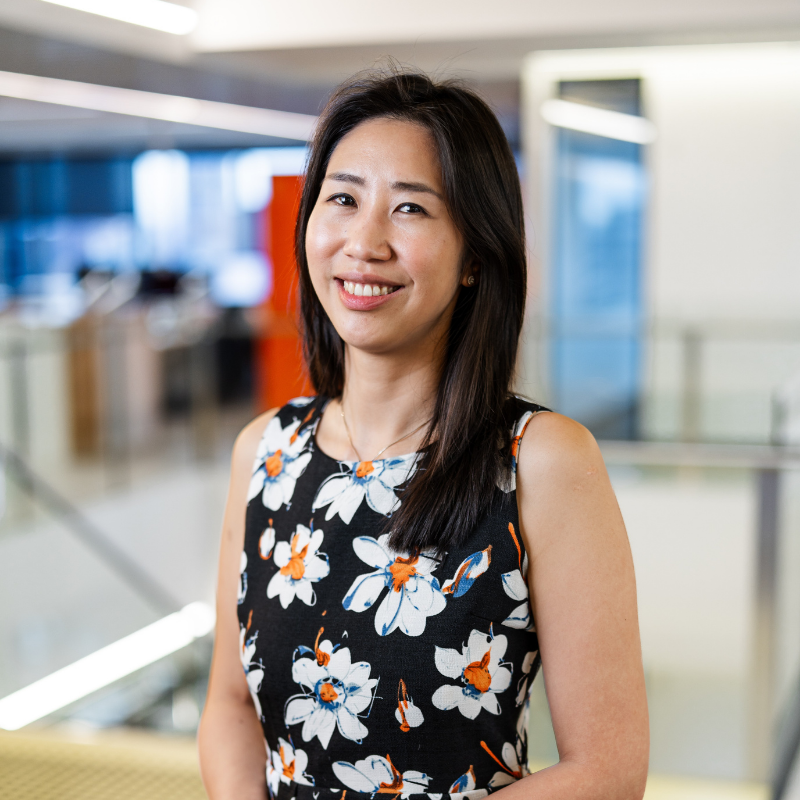 Woman with long black hair and dressed in a black dress with white flowers.