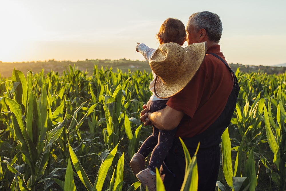 Person holding child in a field on a farm