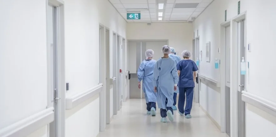 View from behind of four doctors in hospital corridor walking