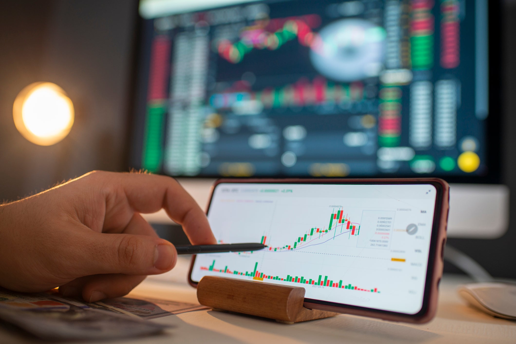 Person holding a pen up to a phone screen showing a graph.