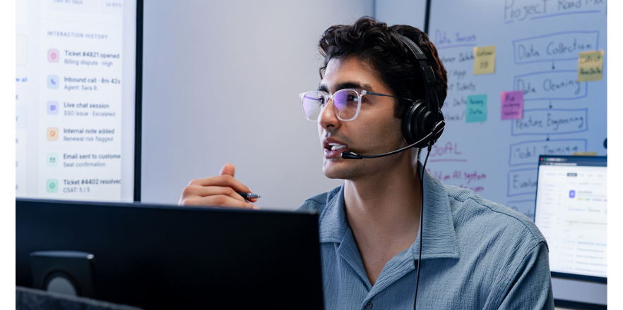 Man with headset on at computer talking.