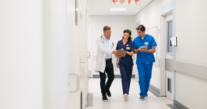 Doctor and surgeon with nurse, walking in hospital hallway