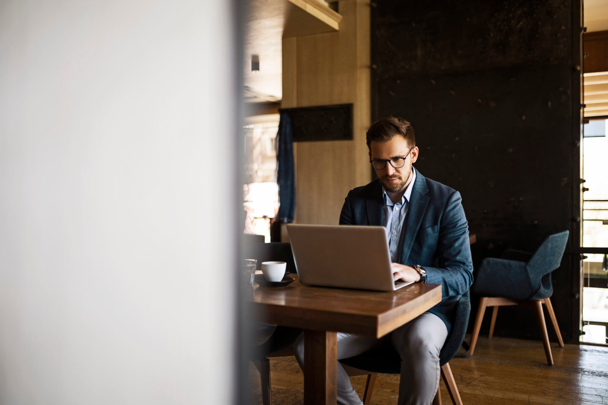Businessman drinking coffee while working on laptop