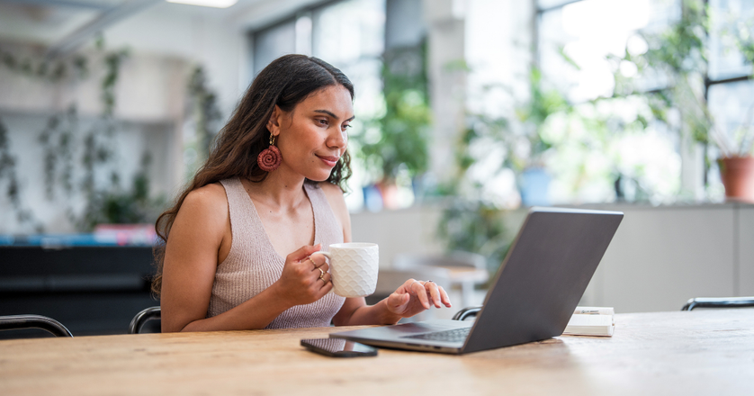 A young adult Aboriginal businesswoman works diligently on her laptop in a modern office.