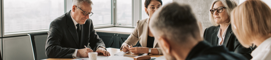 Men and women at boardroom table in meeting.