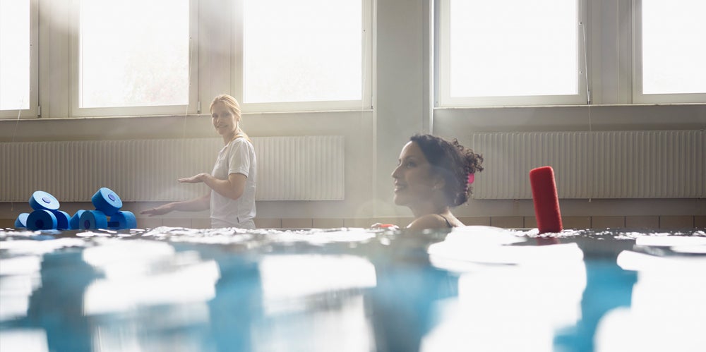 Woman in a pool receiving rehab recovery swimming lessons