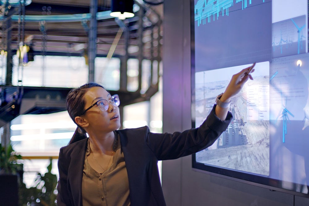 Woman in banking pointing to a screen with data