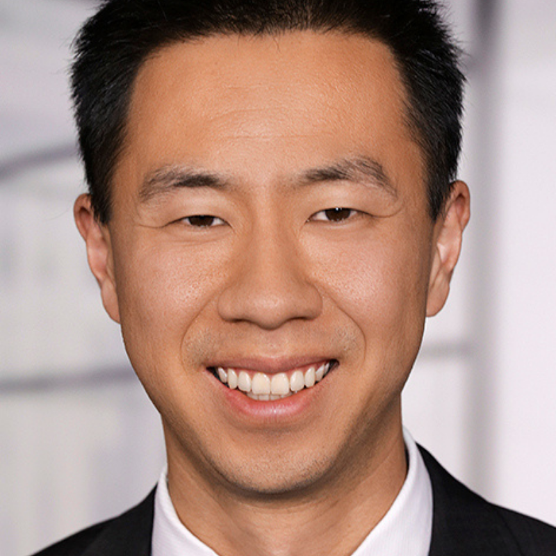 Man smiling and looking at camera with black hair and white shirt and black jacket