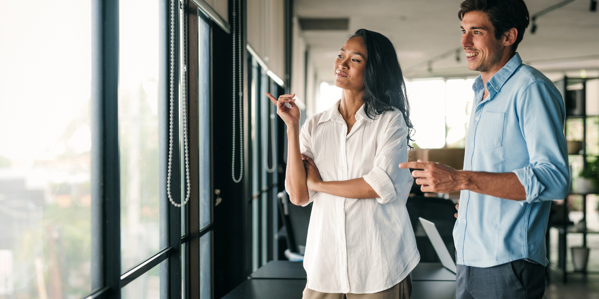 Professional woman and man looking out window.