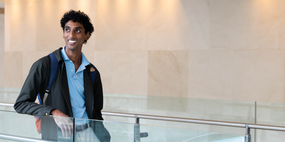 Smiling man standing behind railing.