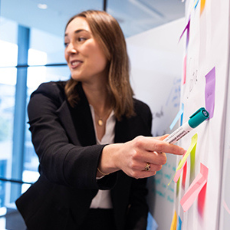 Young business women talking and pointing to a whiteboard as she presents