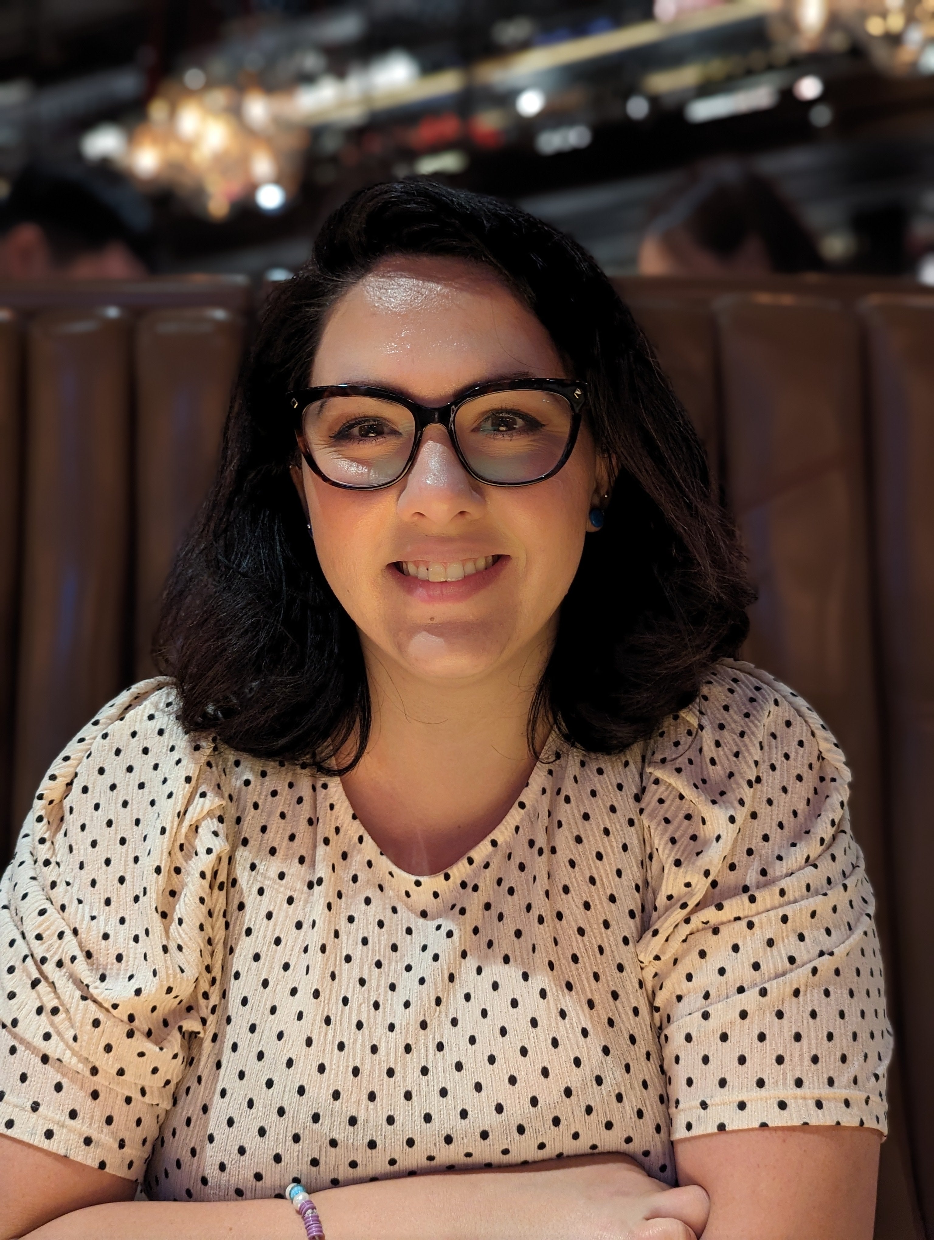 Photo of Bianka Grange, who has dark hair and glasses and sits smiling at the camera.