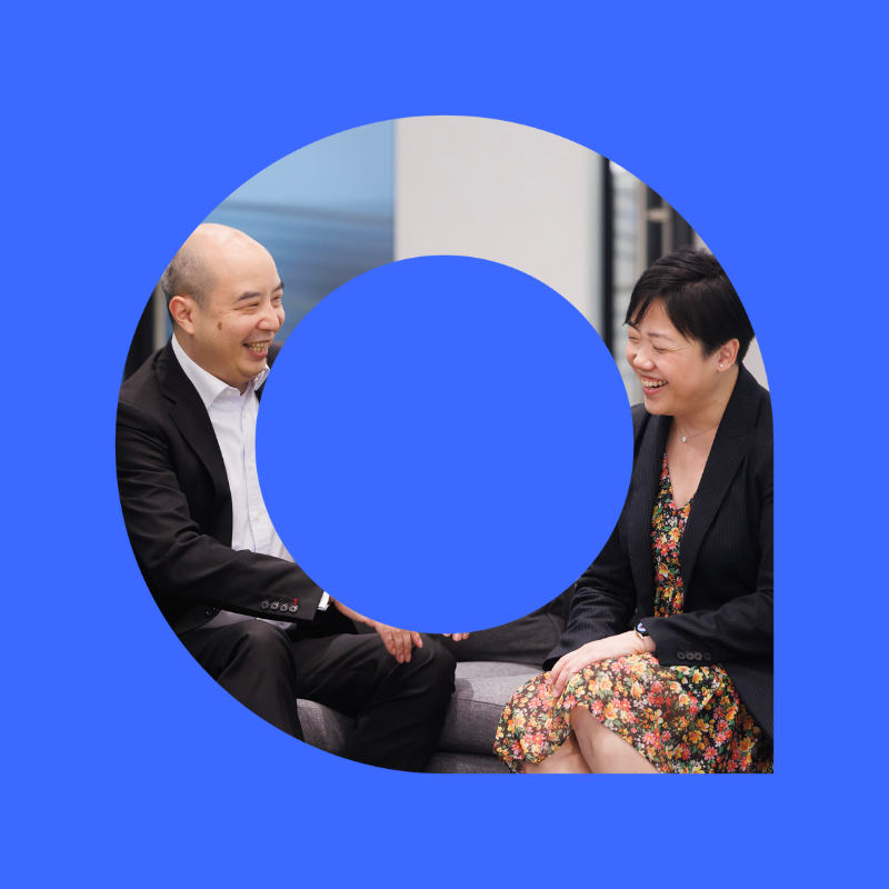 Professional man and woman sit talking and smiling.