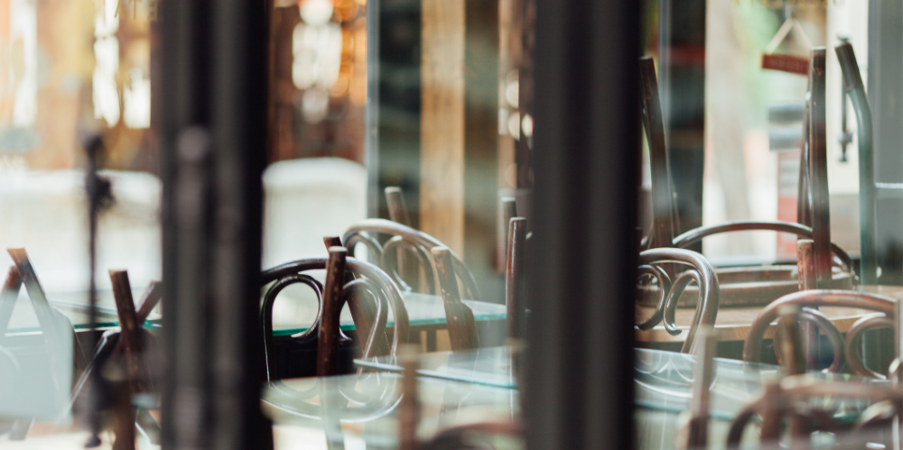 Empty chairs by table seen through glass window in cafe