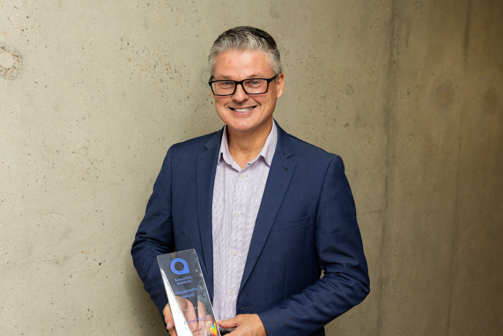 Man in blue business suit smiling at camera with a trophy
