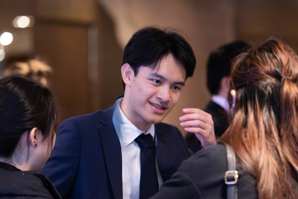 Business man leaning forward and talking to two peopler at an event