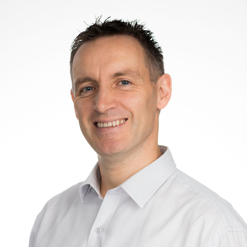 Man in white collared shirt and short dark hair smiling at camera
