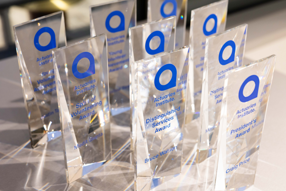 Clear trophies with blue writing set up on a table