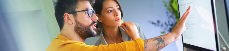 Two people working at a computer screen.
