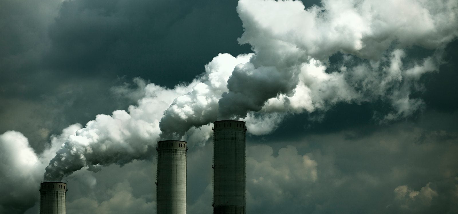 A dreary shot of a power plant, expelling smoke into a dark sky.