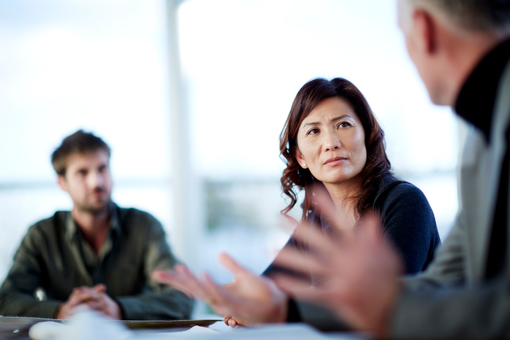 A women engaging in a serious meeting with two male colleagues.
