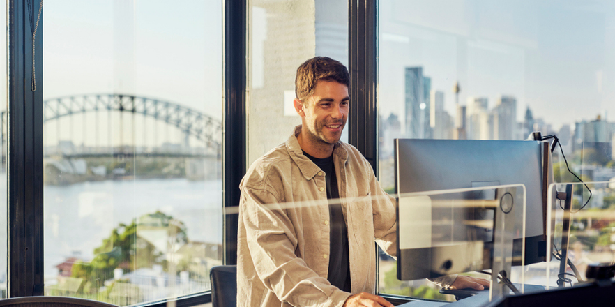 Man at laptop with Sydney harbour in background