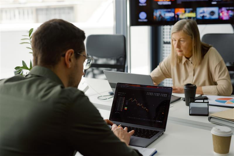 Two people typing at a desk looking at graphs