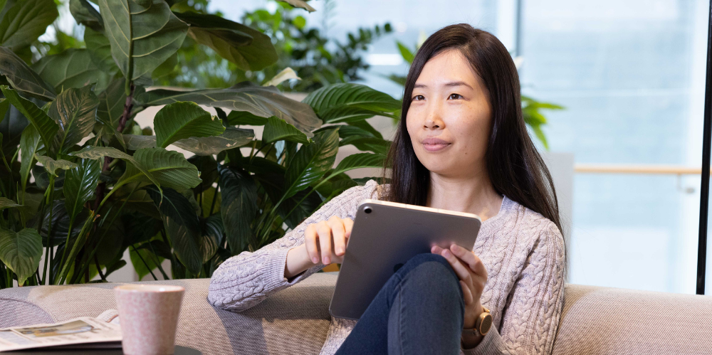 Women with blak hair  sitting on lounge, with ipad and looking away