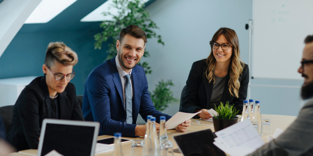 Business people enaged in conversation and smiling sitting around a boardroom table