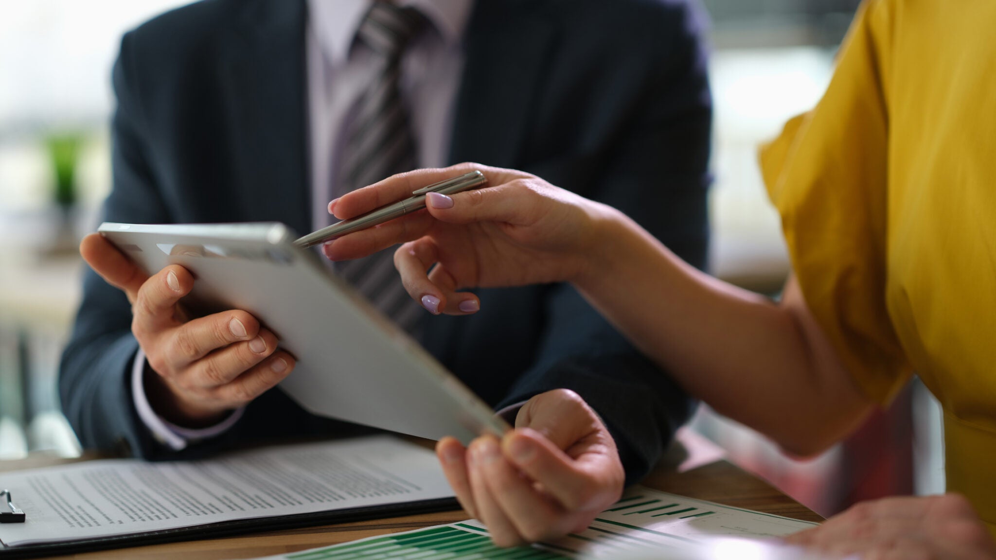 Two business partners are discussing information on tablet computer. Collaborate and discuss project on tablet