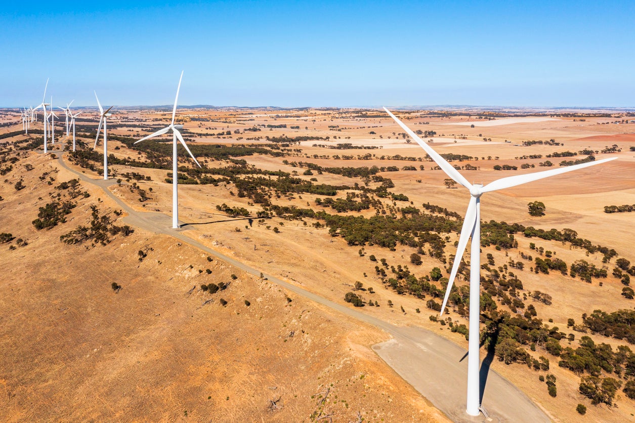 Aerial view of a Wind Farm with blue sky in an open paddock.